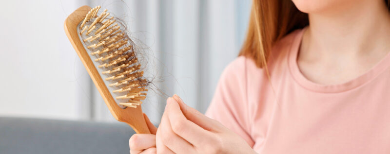 ihminen irrottaa hiuksia hiusharjasta
