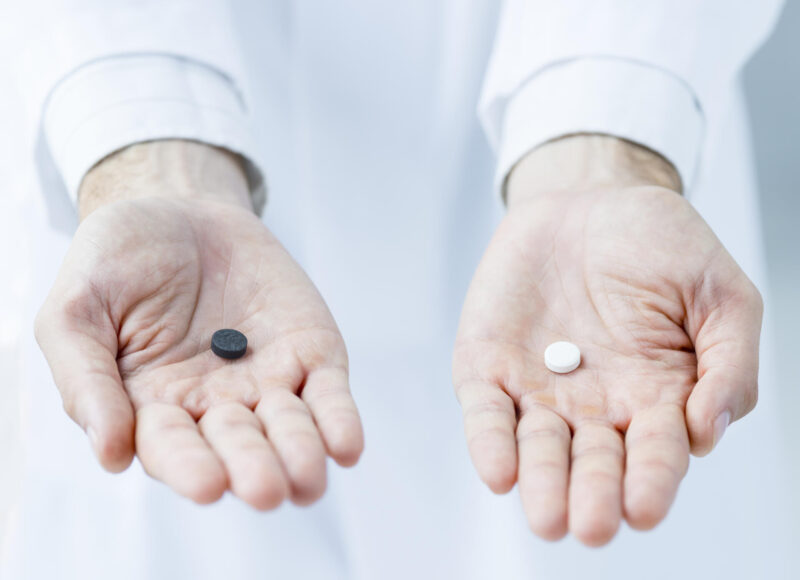 Ihmisen kädessä tumma ja vaalea tabletti.