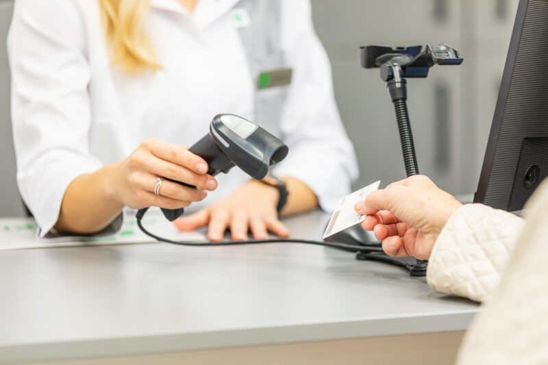 Farmaseutti skannaa asiakkaan Kela-kortin apteekin tiskillä.