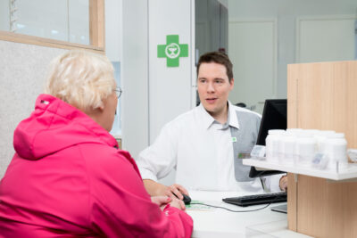 Miesfarmaseutti palvelee naisasiakasta reseptitiskissä.