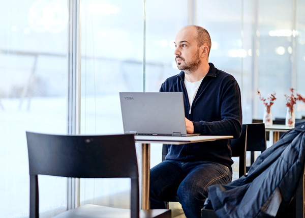 ihminen kannettavan tietokoneen edessä katsoo ikkunasta ulos.