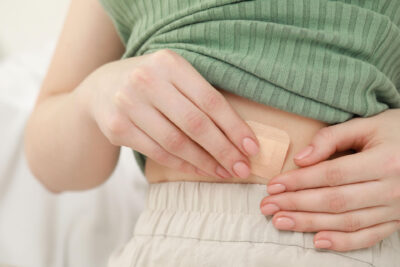 Nainen kiinnittää hormonilaastaria vatsaan.