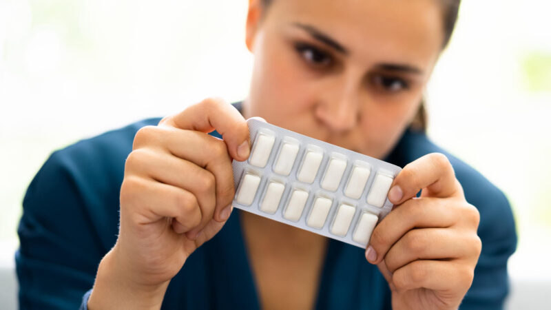 Nainen pitelee nikotiinipurukumipakettia.