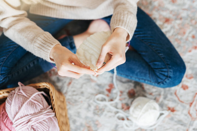 Ihminen neuloo lattialla.