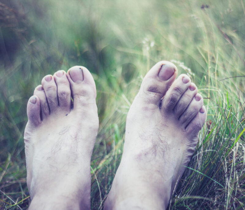 Paljaat jalkaterät heinikossa.