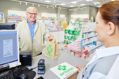 Hymyilevä mies apteekin kassalla.