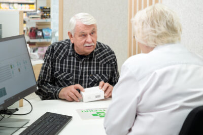 Hämmentynyt iäkäs mies apteekin reseptitiskissä.