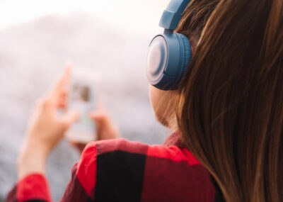 Nainen selaa känykkää kuulokkeet päässä