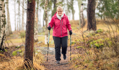 Raija Kaitila sauvakävelemässä syksyisessä metsässä.