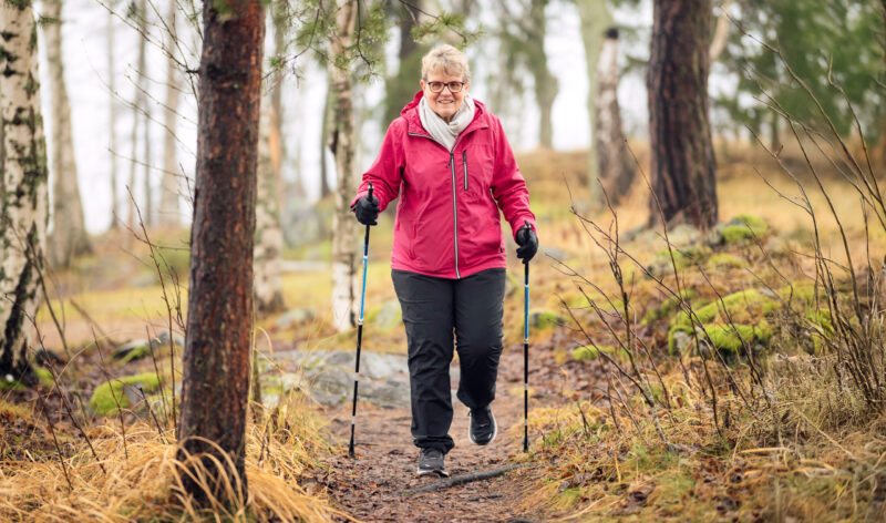Raija Kaitila sauvakävelemässä syksyisessä metsässä.
