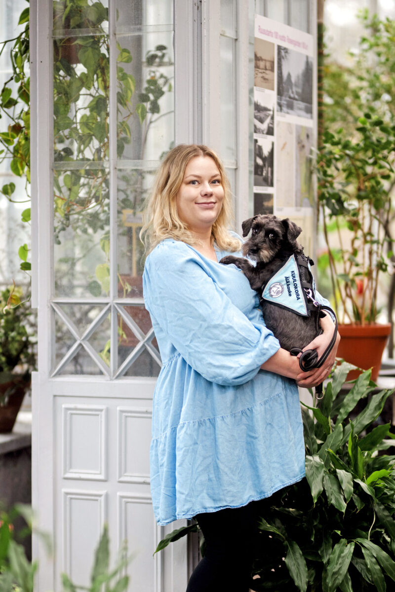 Viivi Kilpeläinen sylissään kuulokoira Hilla.
