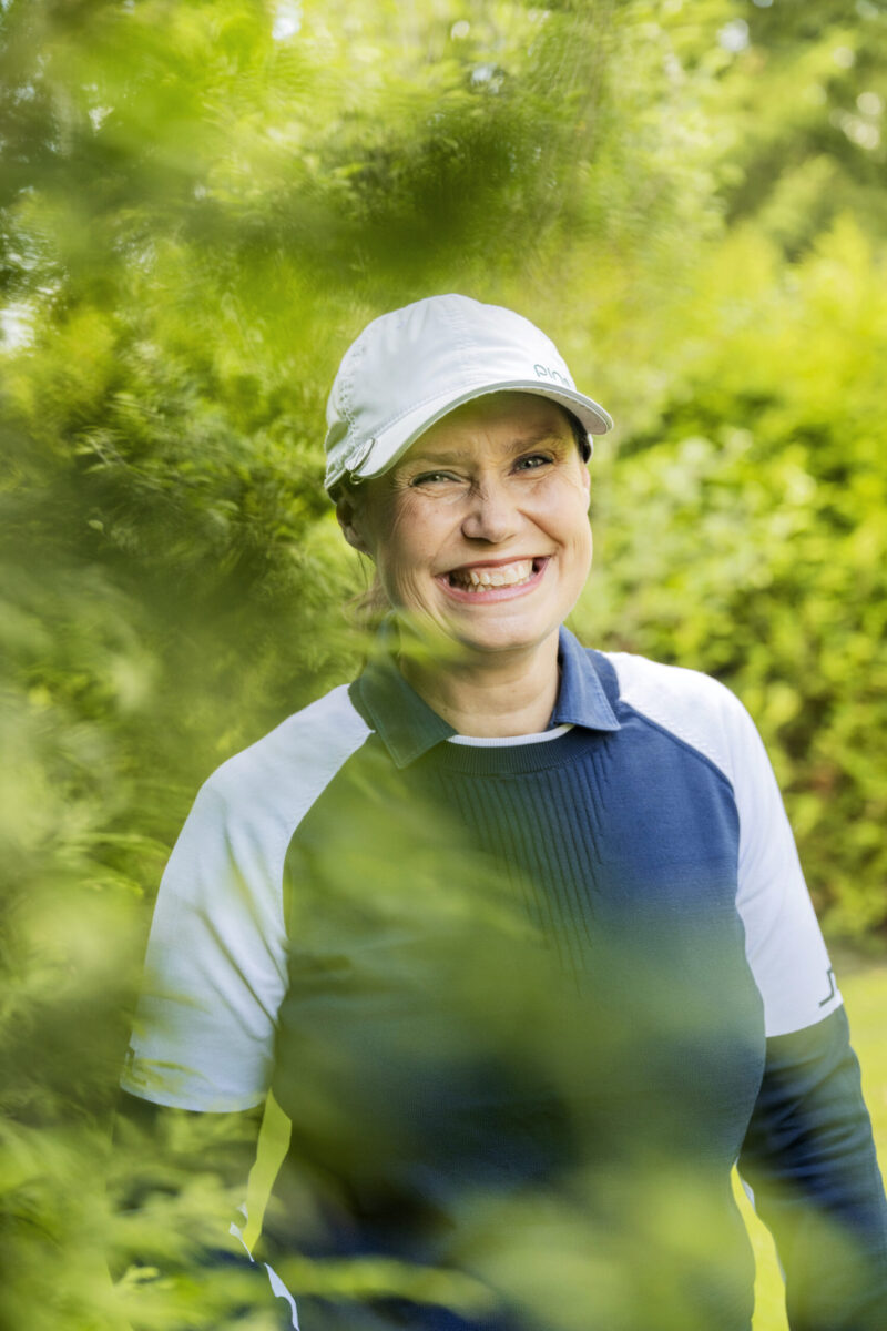 Hanna Partanen lippalakki päässä ulkoilemassa vehreässä metsässä.